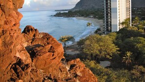 A coastal hotel with a view of the ocean and a mountain in the background. - Stay On The Beach In Makaha   (Waianae)