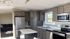 A modern kitchen with grey cabinets, stainless steel appliances, and a large island.