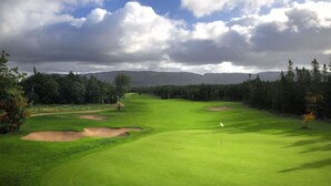 A golf course with bunkers, a flagstick, and a clear sky.