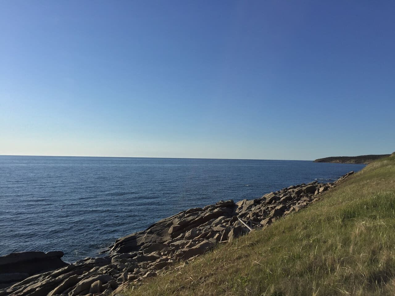 Eine Küstenlandschaft mit felsiger Küste und freiem Blick auf das Meer.