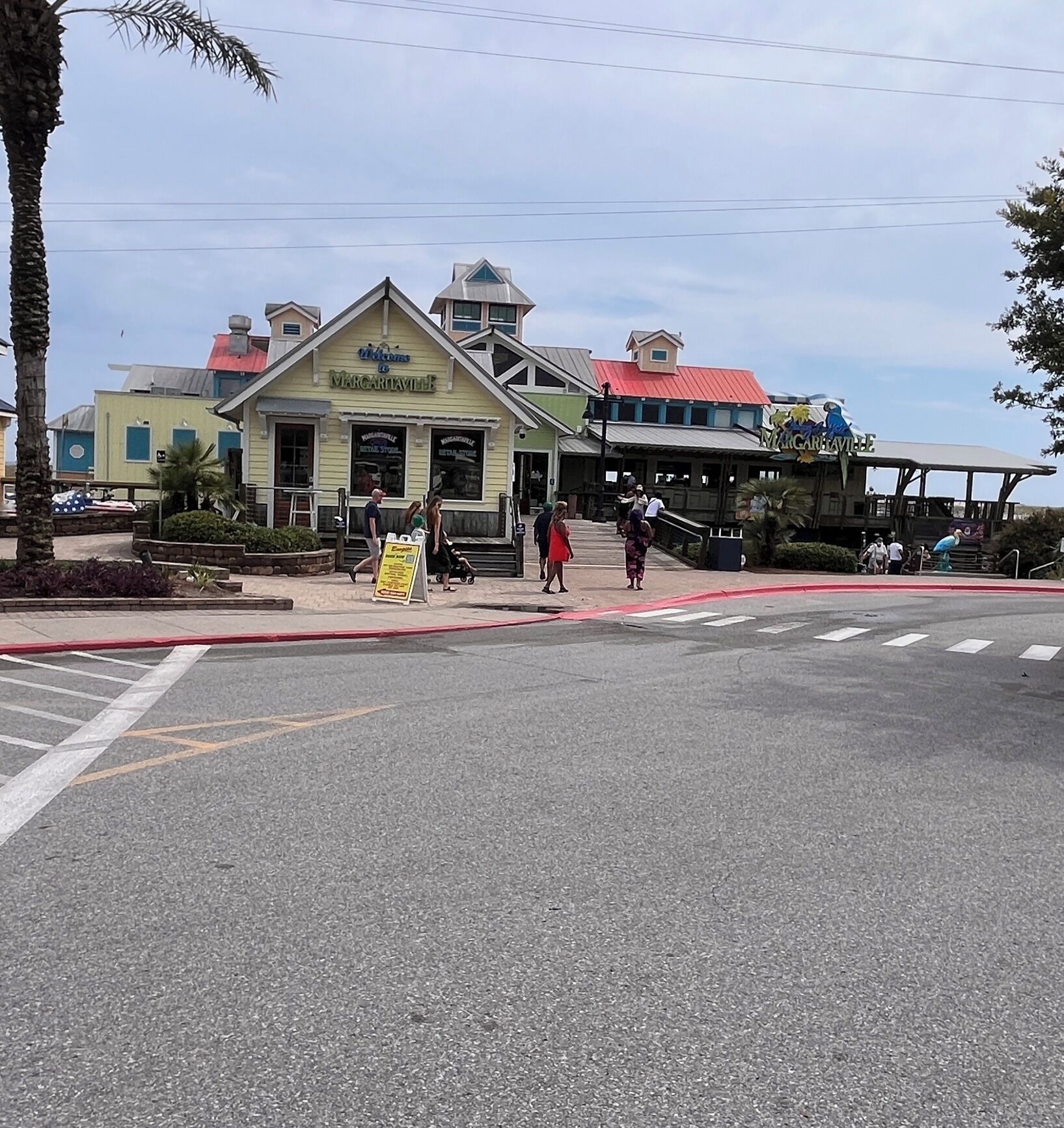 A building with a green facade and a red roof, possibly a restaurant or cafe, with a sign that reads 'Welcome to Margaritaville.'