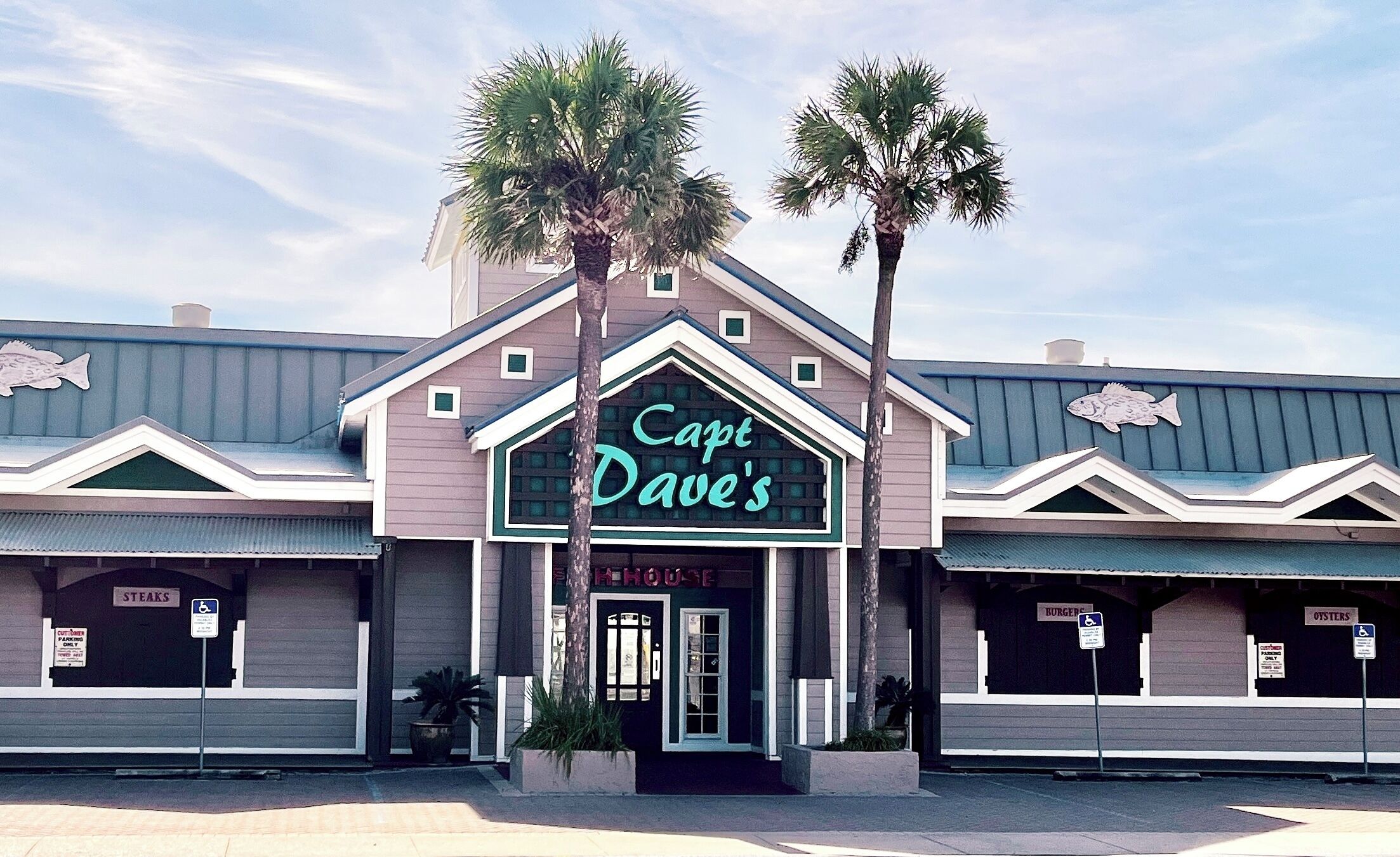 A building with a sign reading 'Capt Dave's' and multiple signs for 'Steaks,' 'R. House,' 'Burger,' and 'Oysters.'