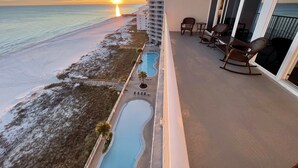 Een balkon met uitzicht op het strand en de oceaan tijdens zonsondergang.