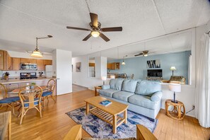 A modern apartment with a dining area, kitchen, living room, and a large window.