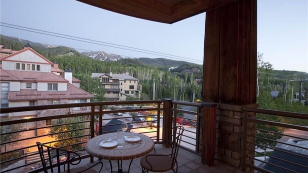 A balcony with a table set for two, overlooking a residential area with houses and a mountain in the background. - Granita 301 (Telluride)