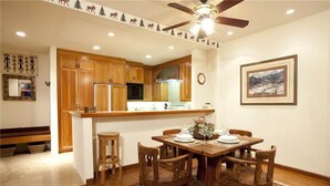 A kitchen with wooden cabinets, a central island, and a dining area with a table and chairs. - Granita 301 (Telluride)