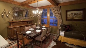 Uma sala de jantar com uma mesa de madeira posta para quatro pessoas, um lustre e um espelho grande acima da mesa.