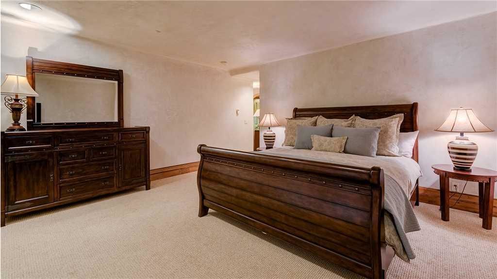 A bedroom with a large wooden bed, a dresser, and two bedside lamps.