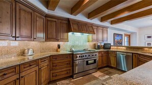 A kitchen with wooden cabinets, a stainless steel stove, and granite countertops. - Plaza 403 (Telluride)