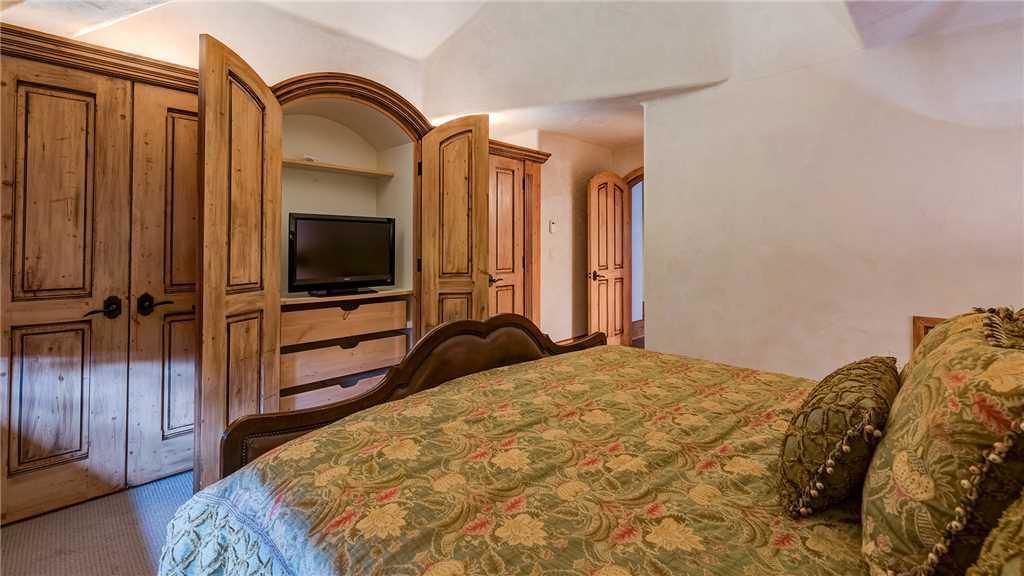 A bedroom with a bed, wooden wardrobe, and a television.