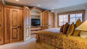 A bedroom with a large bed, wooden wardrobe, and a television. - Plaza 403 (Telluride)