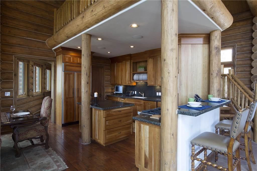L’intérieur d’une cabane en rondins comprend une cuisine, un coin repas et un escalier.