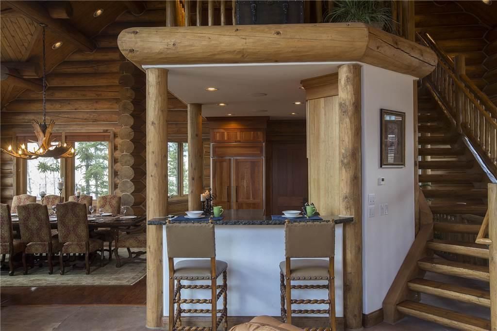 A log cabin interior with a dining area, a kitchen, and a staircase.