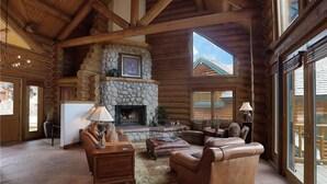 A log cabin interior with a stone fireplace, leather furniture, and large windows. - Sundance Grand Overlook (Telluride)