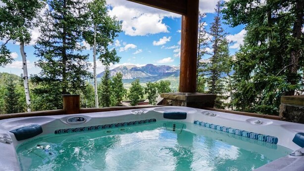 A hot tub with a mountain view, surrounded by trees. - Sundance Grand Overlook (Telluride)