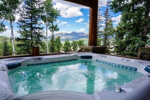 Un bain à remous avec vue sur les montagnes, entouré d’arbres.