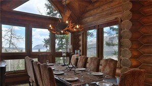 A dining room with a long table set for six, large windows, and a rustic wooden ceiling. - Sundance Grand Overlook (Telluride)