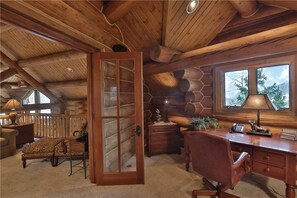 A log cabin interior with a wooden desk, chair, and a large window. - Sundance Grand Overlook (Telluride)