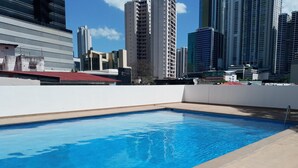 Ein Pool auf dem Dach mit Blick auf die Stadt, umgeben von Hochhäusern.