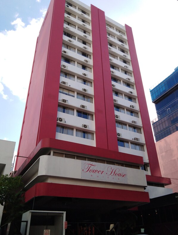 Un immeuble imposant à la façade rouge et blanche, portant l’inscription « Tower House ».