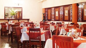 Ein Restaurant mit mehreren Tischen und Stühlen, Holzwandverkleidung und einem Kronleuchter.