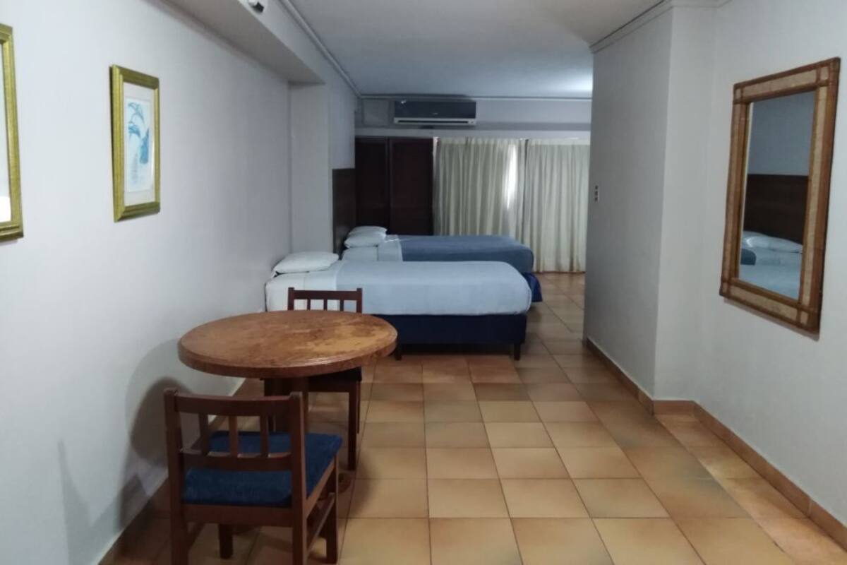 Une chambre d’hôtel avec un lit, une petite table avec des chaises et un miroir au mur.