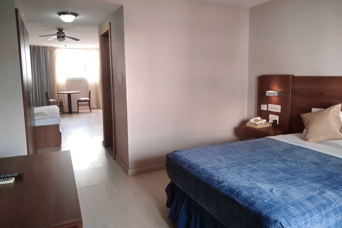 Une chambre d’hôtel comprenant un lit, une table de chevet et un bureau avec une chaise.