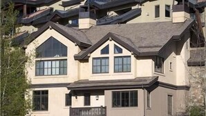 A multi-story house with a stone facade, multiple balconies, and a mountainous backdrop. - Belvedere Park 1 (Telluride)