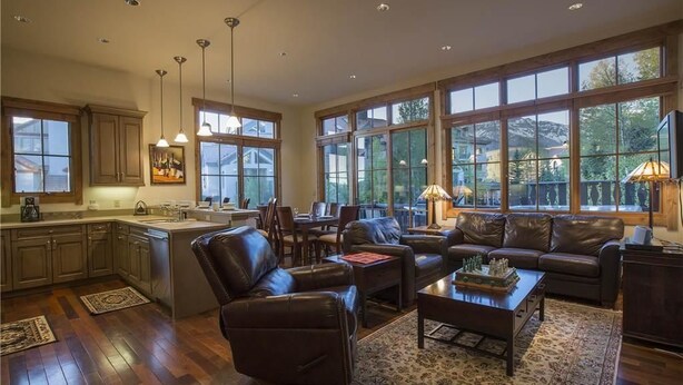 A spacious living area with a large window, a kitchen with wooden cabinets, and a dining area. - Belvedere Park 1 (Telluride)