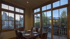 A dining area with a table set for four, large windows, and a view of a mountainous landscape. - Belvedere Park 1 (Telluride)