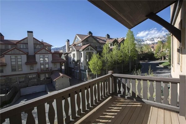 A balcony with a view of a residential area, including houses and a mountain in the background.