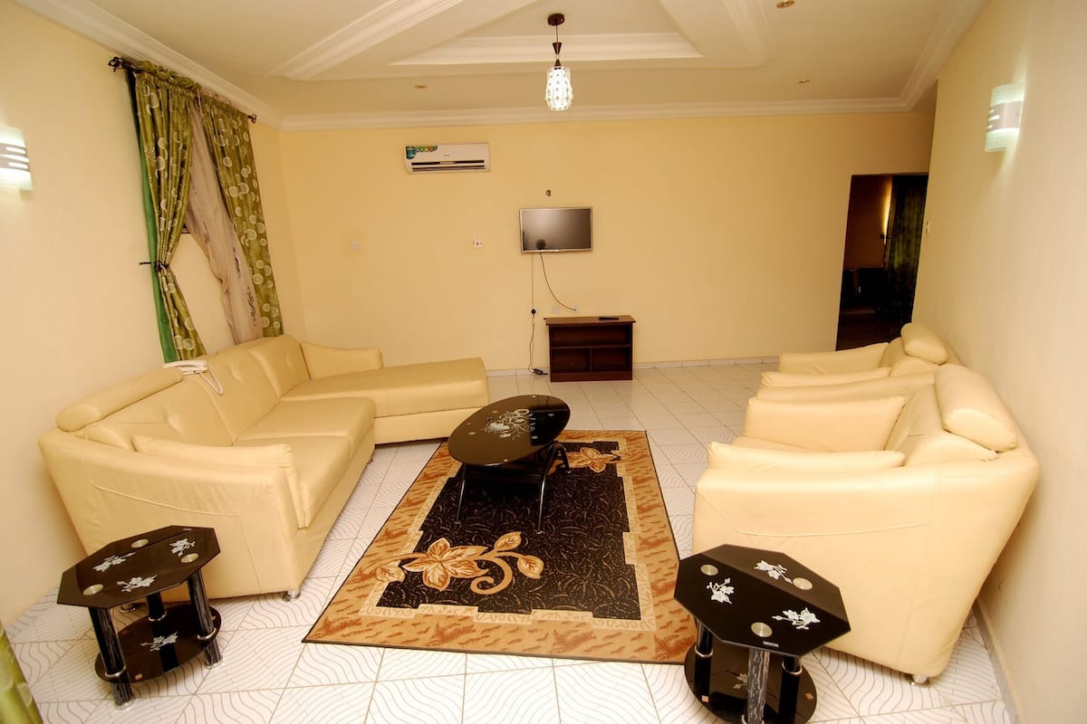 A living room with a beige sofa set, a coffee table, and two side tables.