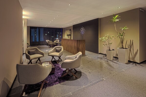 A modern reception area with seating, a reception desk, and decorative plants.