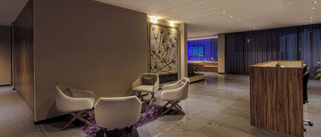 Um lobby moderno com balcão de recepção, área de estar e um painel decorativo.