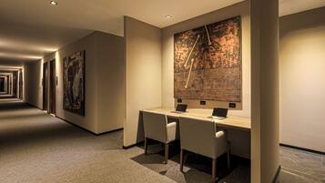 A modern hotel lobby with a long corridor, a reception desk, and artwork on the walls.