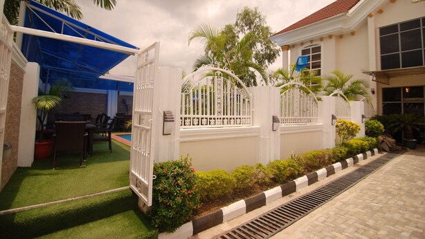 A gated residential area with a pool, outdoor seating, and a well-maintained garden. - The Grosvenor Suite (Abuja)
