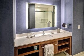 A bathroom with a wooden vanity, a large mirror, and a glass shower enclosure.