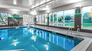 Ein Hallenbad mit klarem Wasser, einer Rettungswache und Blick ins Freie durch große Fenster.