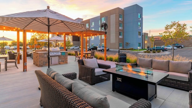 Eine Außenpatio-Terrasse mit Sitzgelegenheiten, einem Grill und Sonnenschirmen.