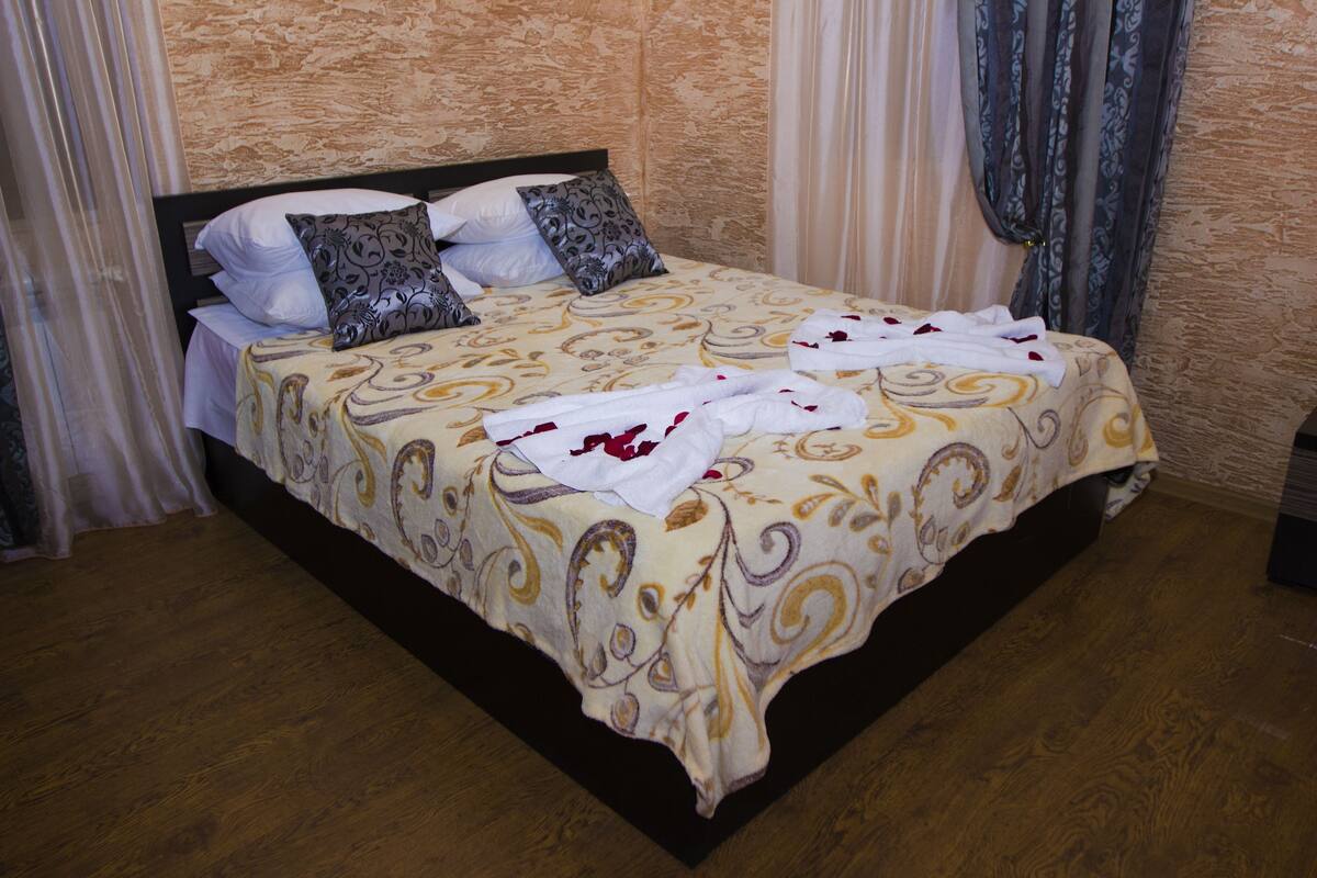 Un lit bien fait, avec une couvre-lit à motifs, des oreillers et une serviette blanche posée sur le lit.
