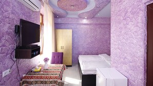 A bedroom with a bed, a TV, a wardrobe, and a small table with a vase. - Planet Yerevan Hotel (Yerevan)