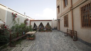 A courtyard with a brick floor, wooden benches, and potted plants. - Planet Yerevan Hotel (Yerevan)