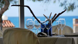 A table set for dining with wine glasses and decorative branches, overlooking the sea. - Residence le 4 stagioni (Menfi)