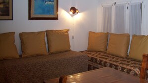 A cozy room with a sofa, a table, and a wall-mounted light fixture.