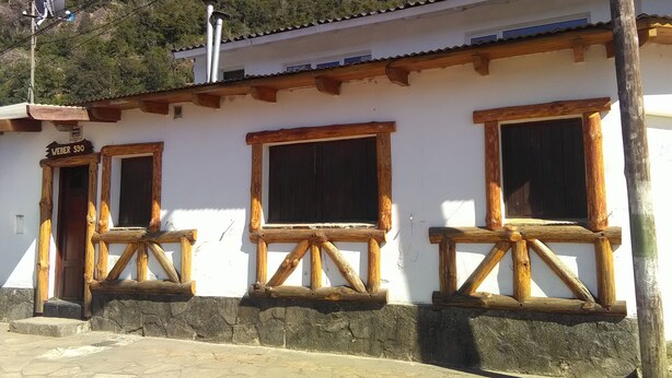 A building with a white facade, wooden window frames, and a stone-paved entrance.