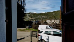 A view from inside a building looking out to a street with parked cars and a hilly landscape in the background.