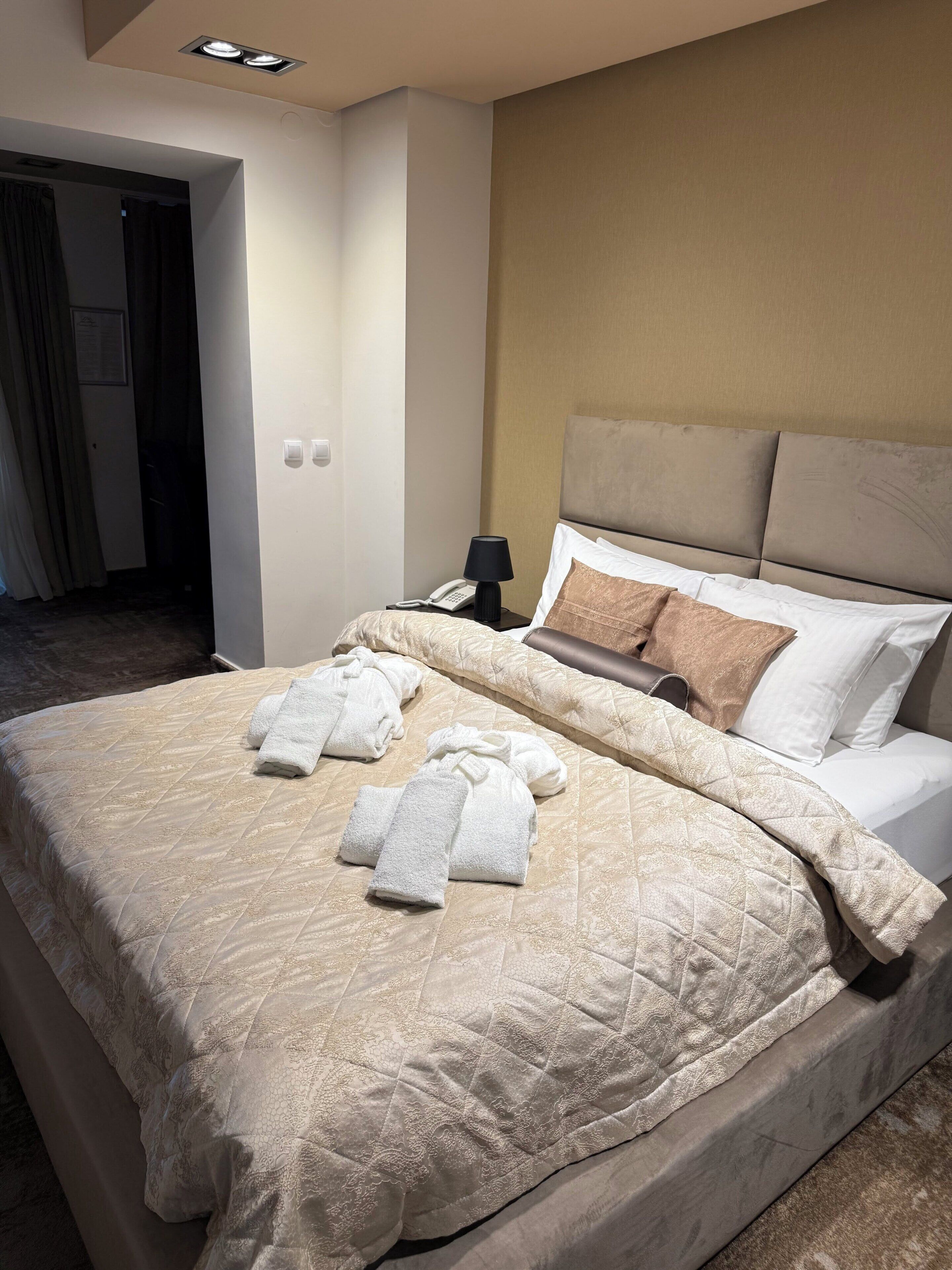 A hotel room with a bed, a nightstand with a lamp, and towels on the bed.