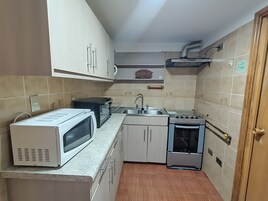A compact kitchen with a microwave, stove, sink, and cabinets.
