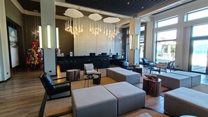 A spacious lobby with a reception desk, modern seating arrangements, and large windows offering views of the outdoors. - Apart Enjoy Pucon (Pucón)