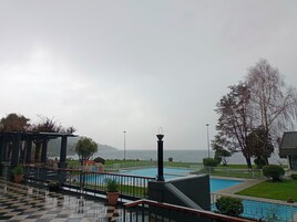 Zona de piscina con vista al mar, un quiosco y suelo a cuadros.